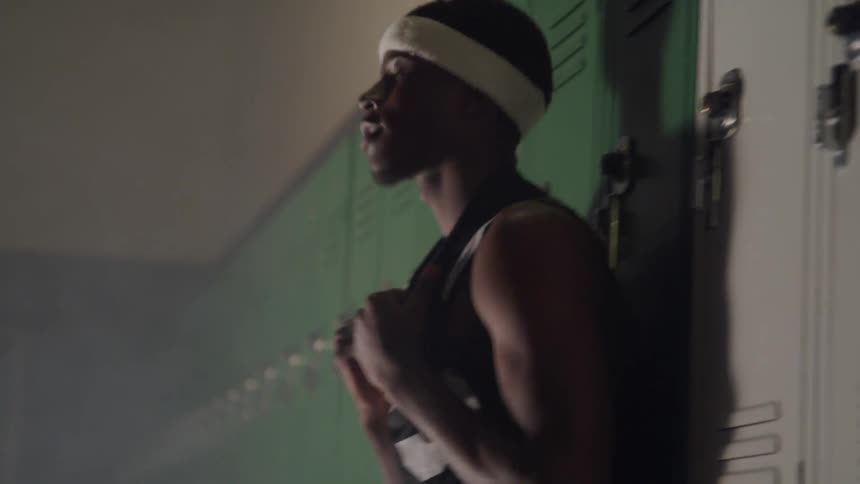 A man in a locker room leaned up against a locker