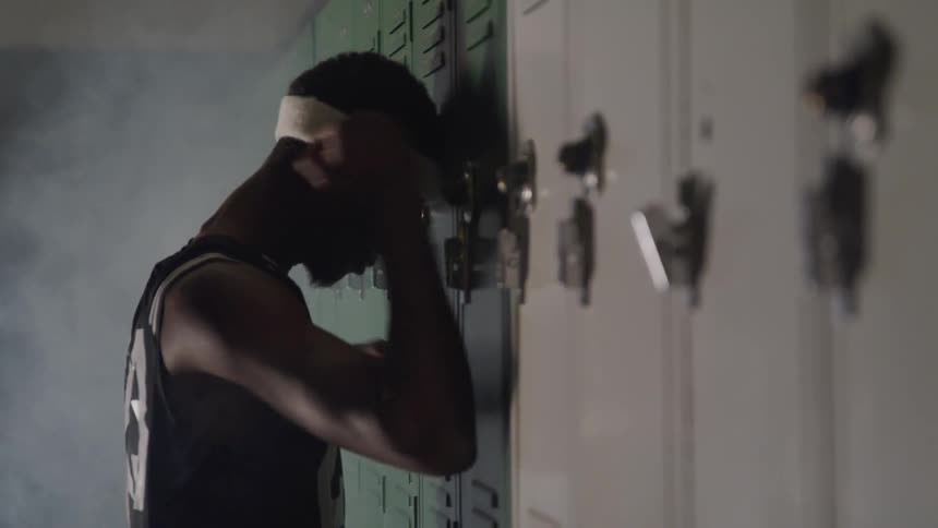 Man leans head against locker knocking on it