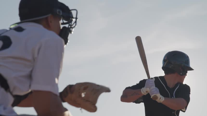 A catcher catches the baseball after the hitter swings and misses