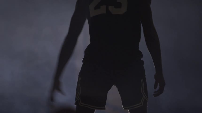 A man dribbles a basketball on a foggy court