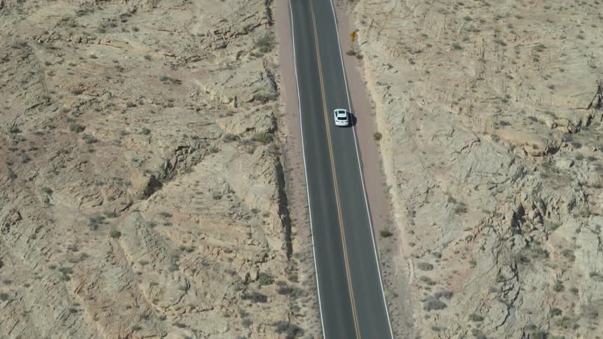 An aerial view of a car in the middle of desert road