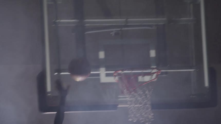 Two men play basketball on foggy darkened interior basketball court