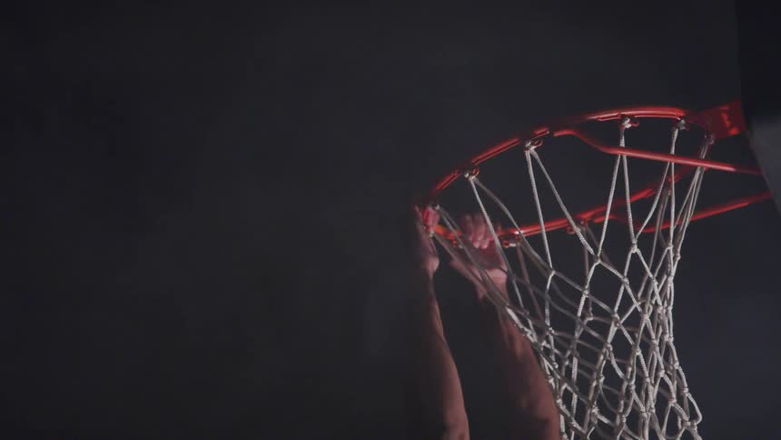 Man dunks basketball then hangs on hoop