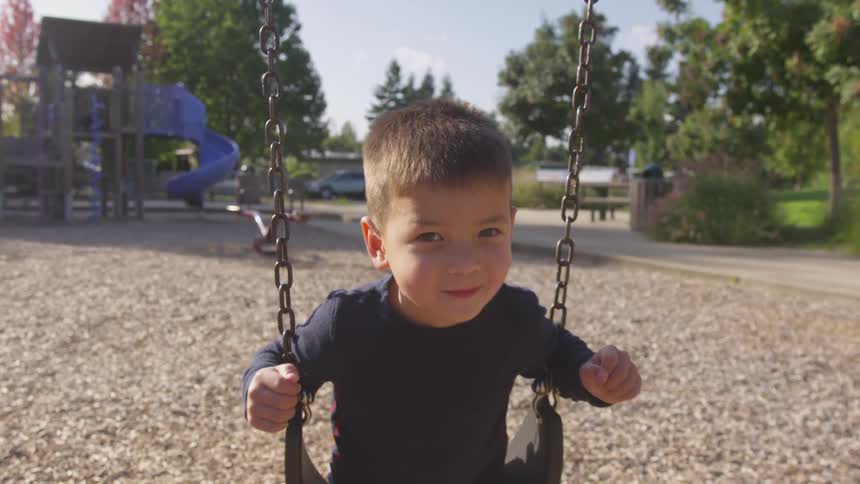 Child swings and looks at the camera in the playground