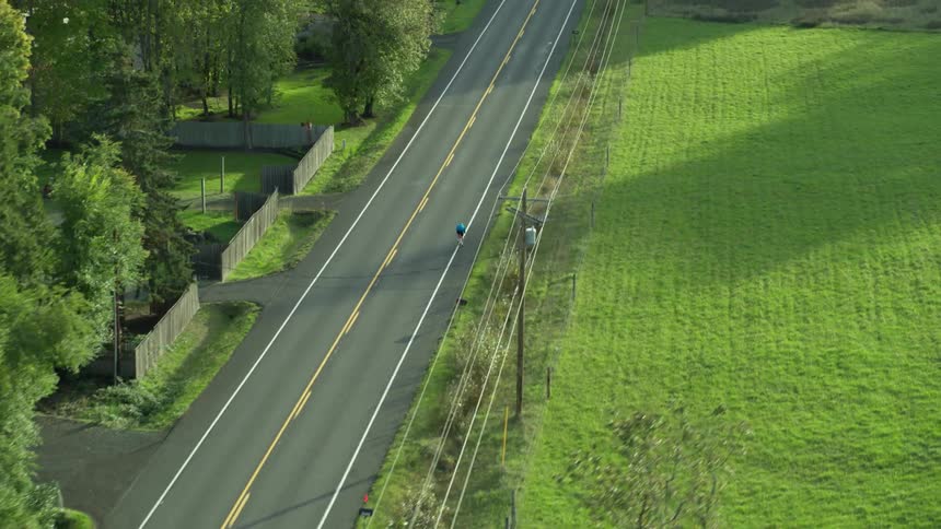 Bicyclist rides along highway through countryside