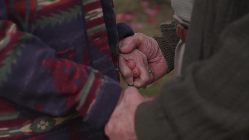 An elderly couples clasped hands