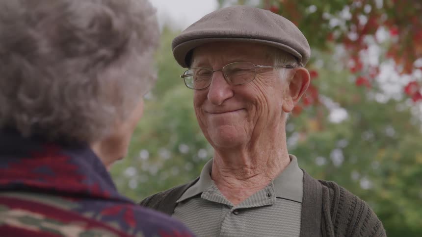 Senior man and woman look at each other under the tree in the public park