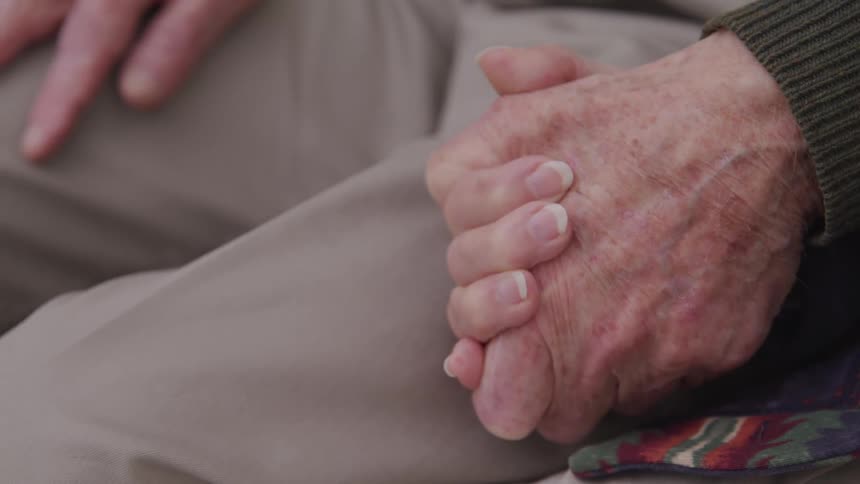 Older person holds hands with a younger person