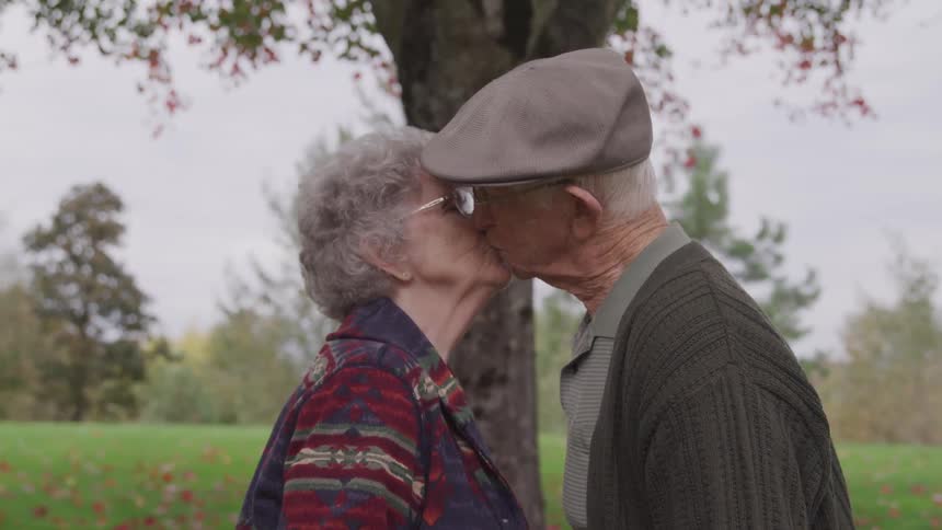 An elderly man and woman kiss