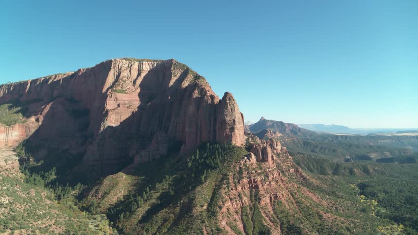 Mountains covered with greenery stand under a blue sky