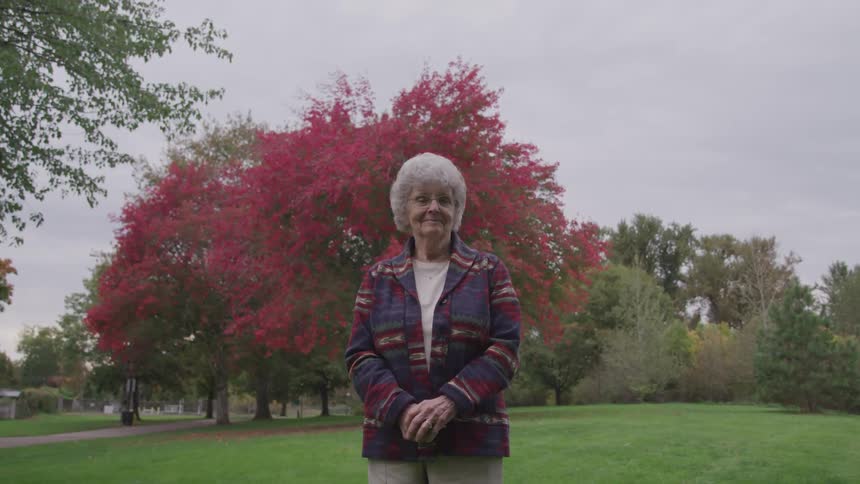 Woman stands in park near flowering trees