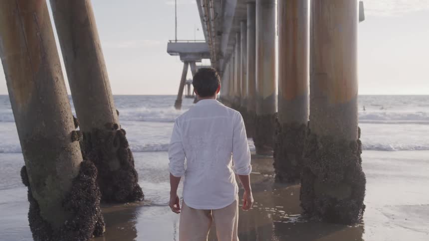 A man with white shirt contemplatively thinking on the beach