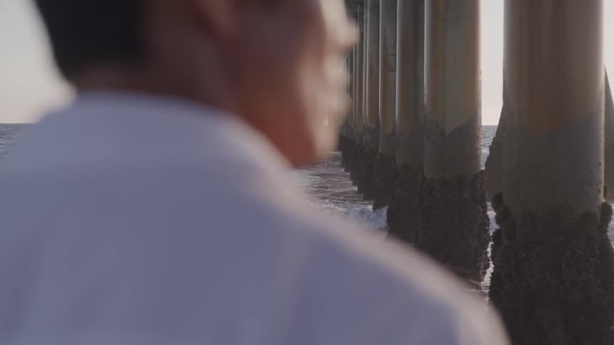 A person is standing under a bridge near a body of water