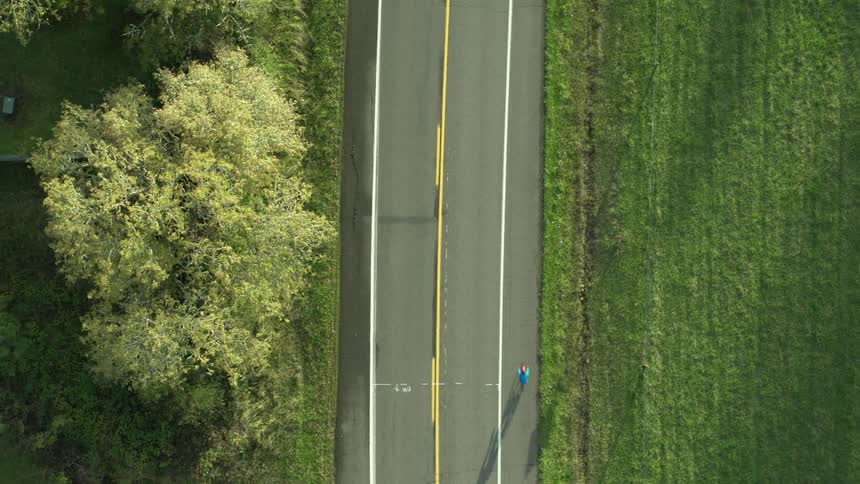 Aerial of a person running on a road in the countryside