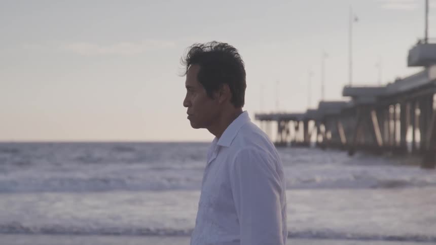 An old looking man walking on the beach