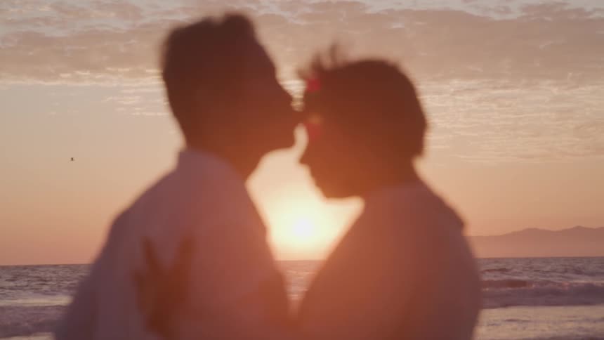 Man and woman dance on the beach at sunset