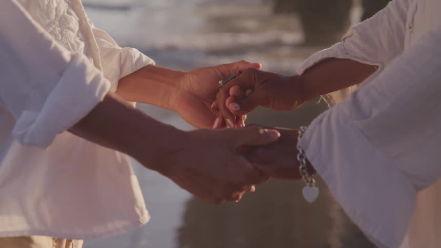 An old couple holding hands on the beach
