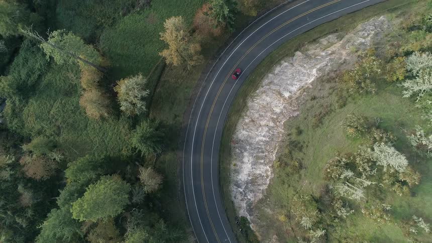 An aerial view of a car driving on a road