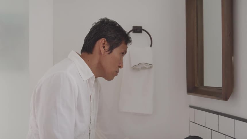 A portrait of a middle aged man looking through the mirror
