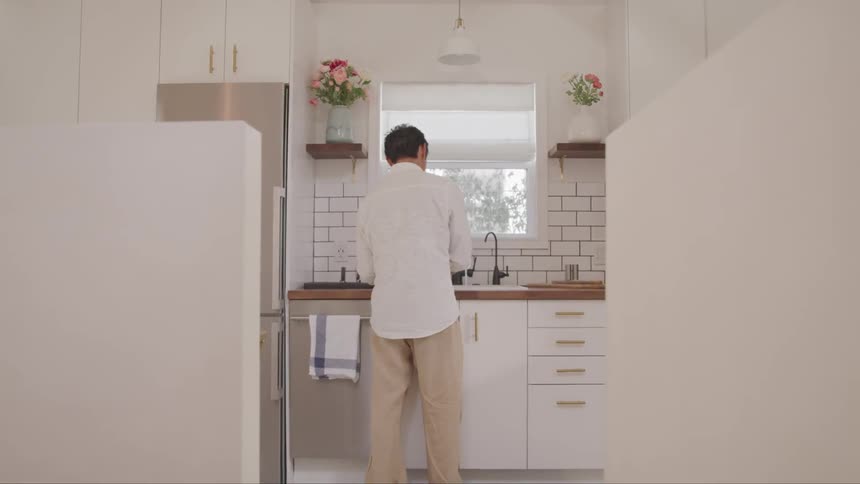 A man washes dishes at a sink in a modern kitchen