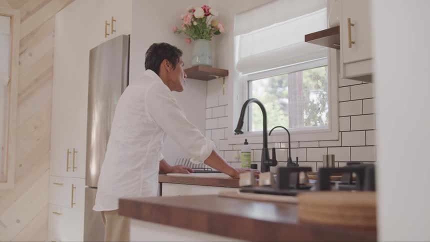 A man stares outside while at the sink