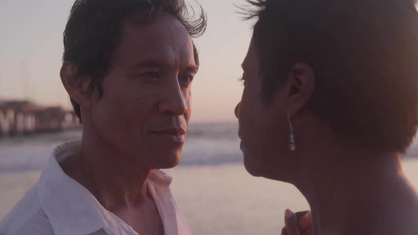 A man and woman staring face to face romantically at the coastal