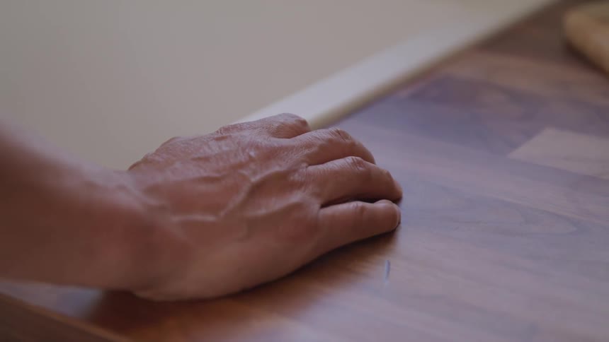 A persons hand is resting on the edge of a table