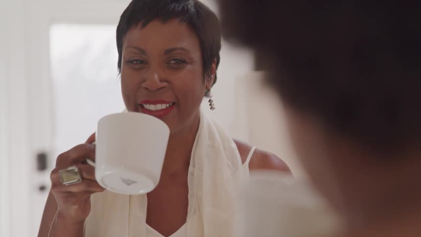 A woman is talking to someone while drinking coffee