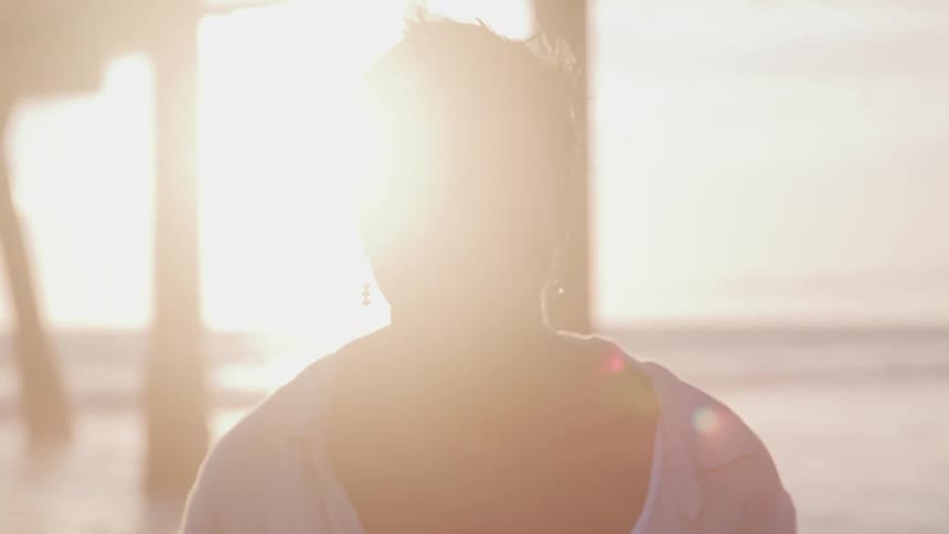 A portrait of a woman under the sun flare at the beach
