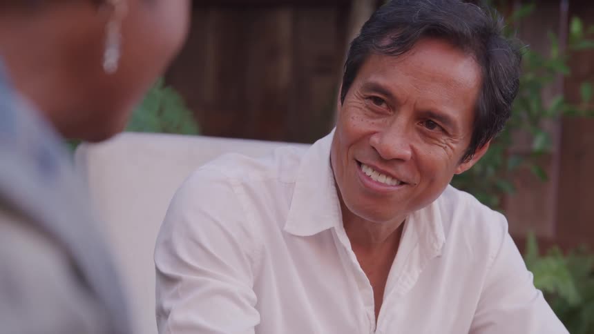 Man smiles as he talks to a woman wearing earrings