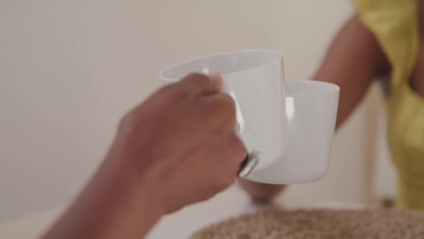 Two people toast their mugs together