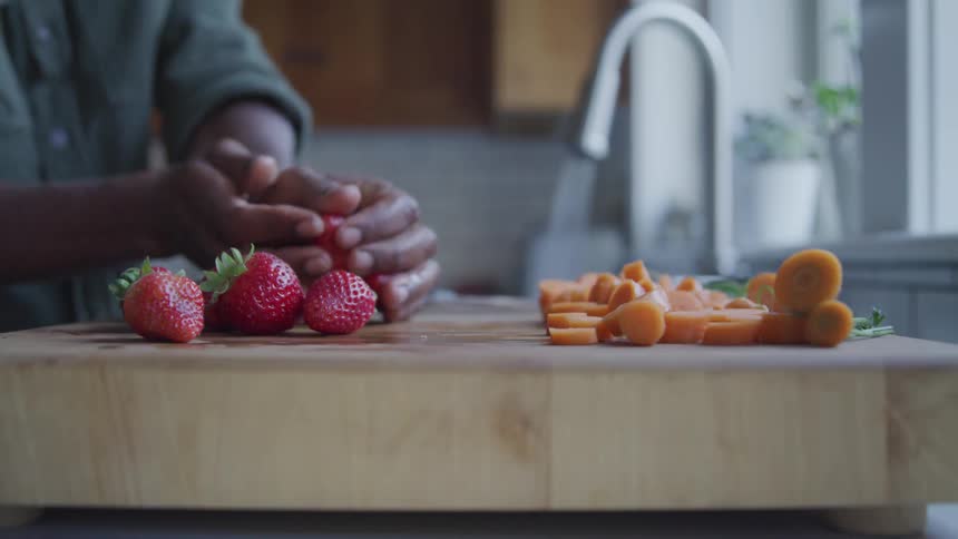 A person taking strawberries from a cutting board and washing it in a sink