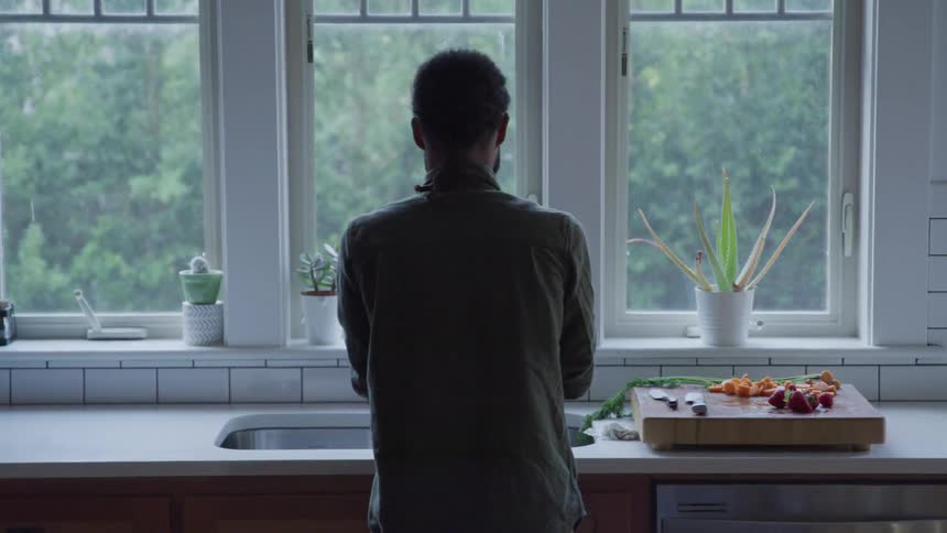 Man washing fruit on kitchen sink in front of window