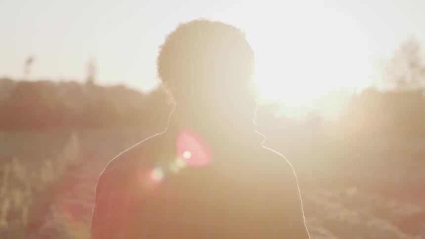 A man in a flannel shirt stands in a field