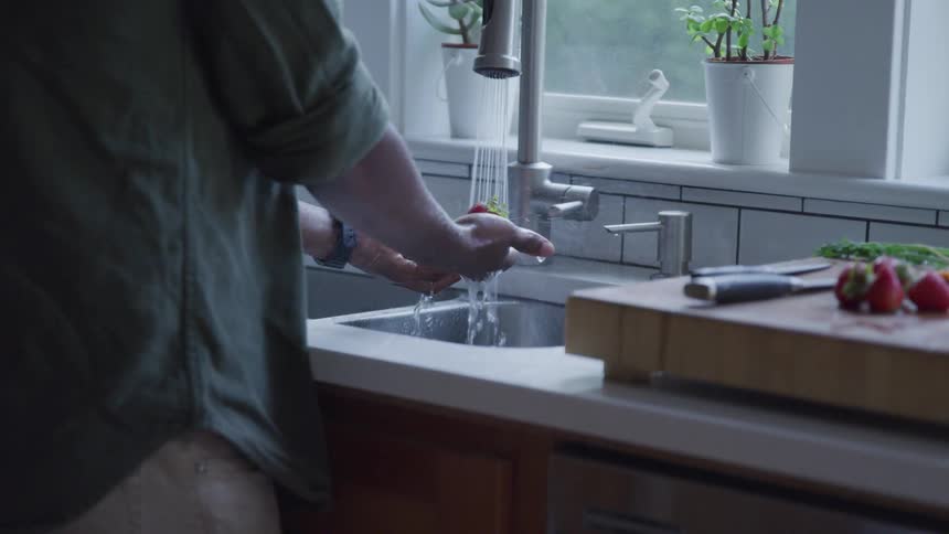 A woman washing hand in the sink at the kitchen