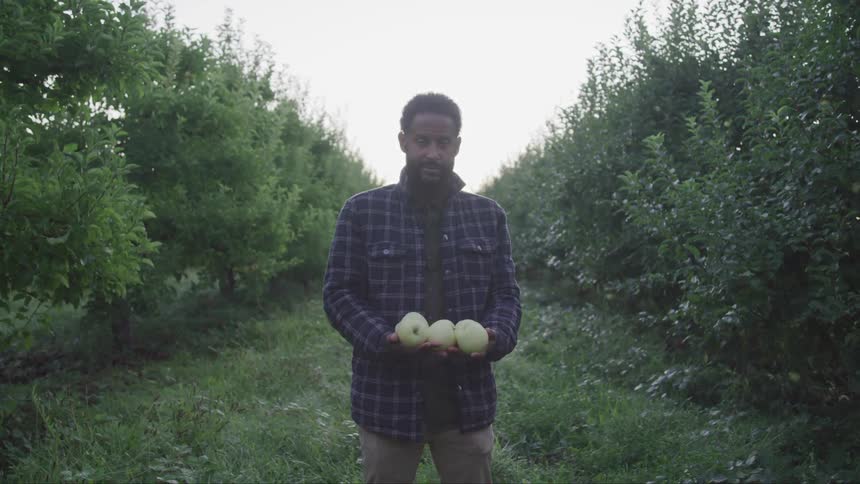A man stands holding fruit