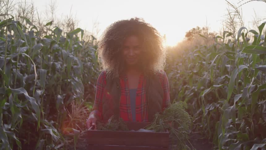 A woman smiles holding produce