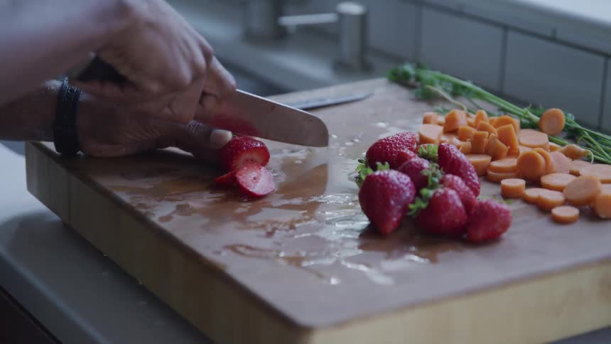 A man cutting fruits on the kitchen table