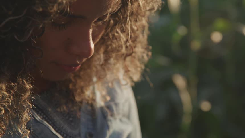 A young girl sits outdoors and stares at the ground