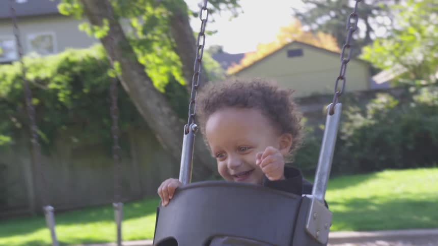 Grandfather swinging his grandson in a bucket swing in the backyard