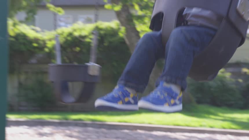 A man pushes a toddler in a swing