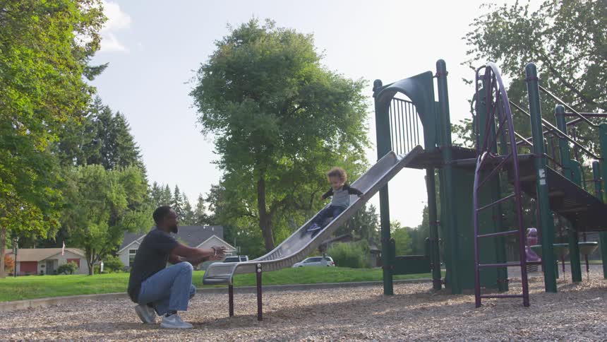 A child slides down in the park into a parents arms