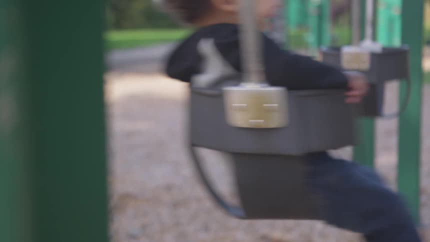 A young child is swinging on a swing at a playground
