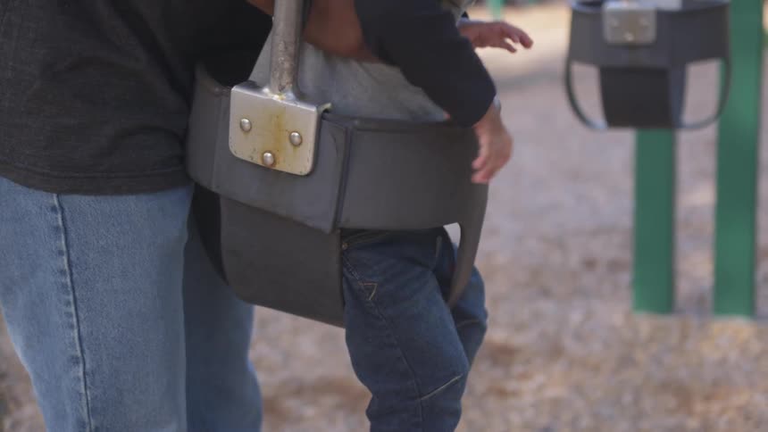 A parent puts their child in the swing
