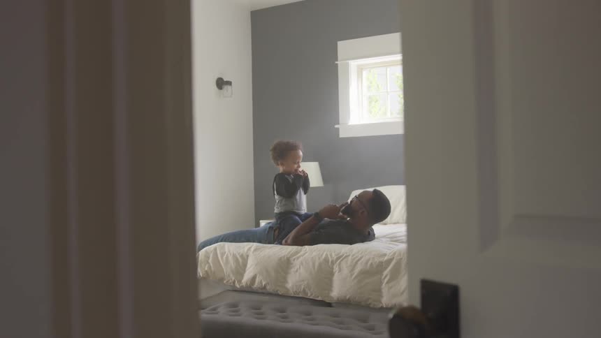 Father and son playing on the bedroom