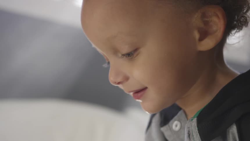 A child smiles while looking down