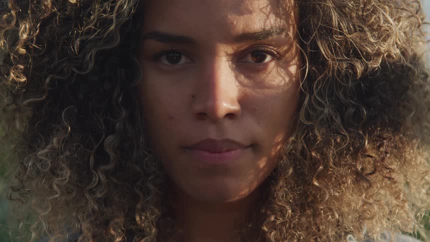 A young black woman raising her head to look into the camera