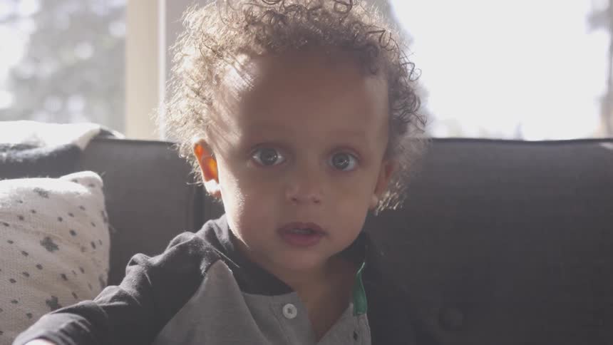 A child is holding up a toy and sitting on a couch