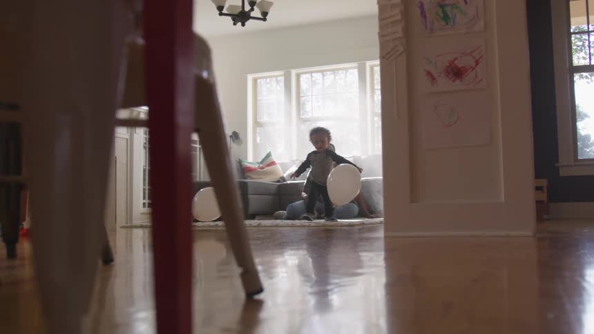 Father watches his sonplay with balloons sunny living room