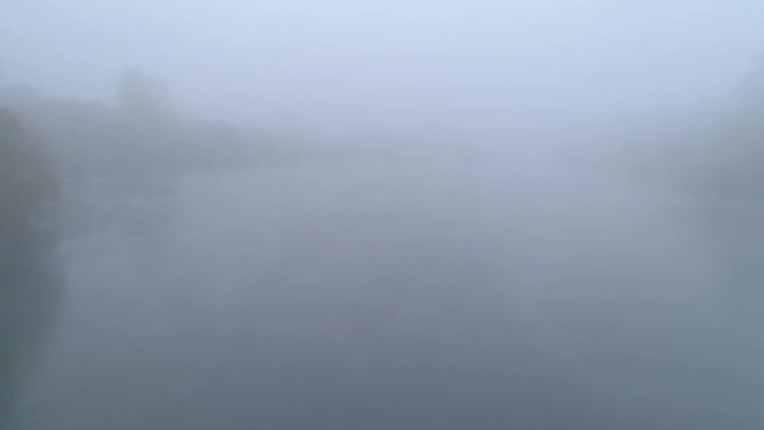 Dense fog hovers above a river